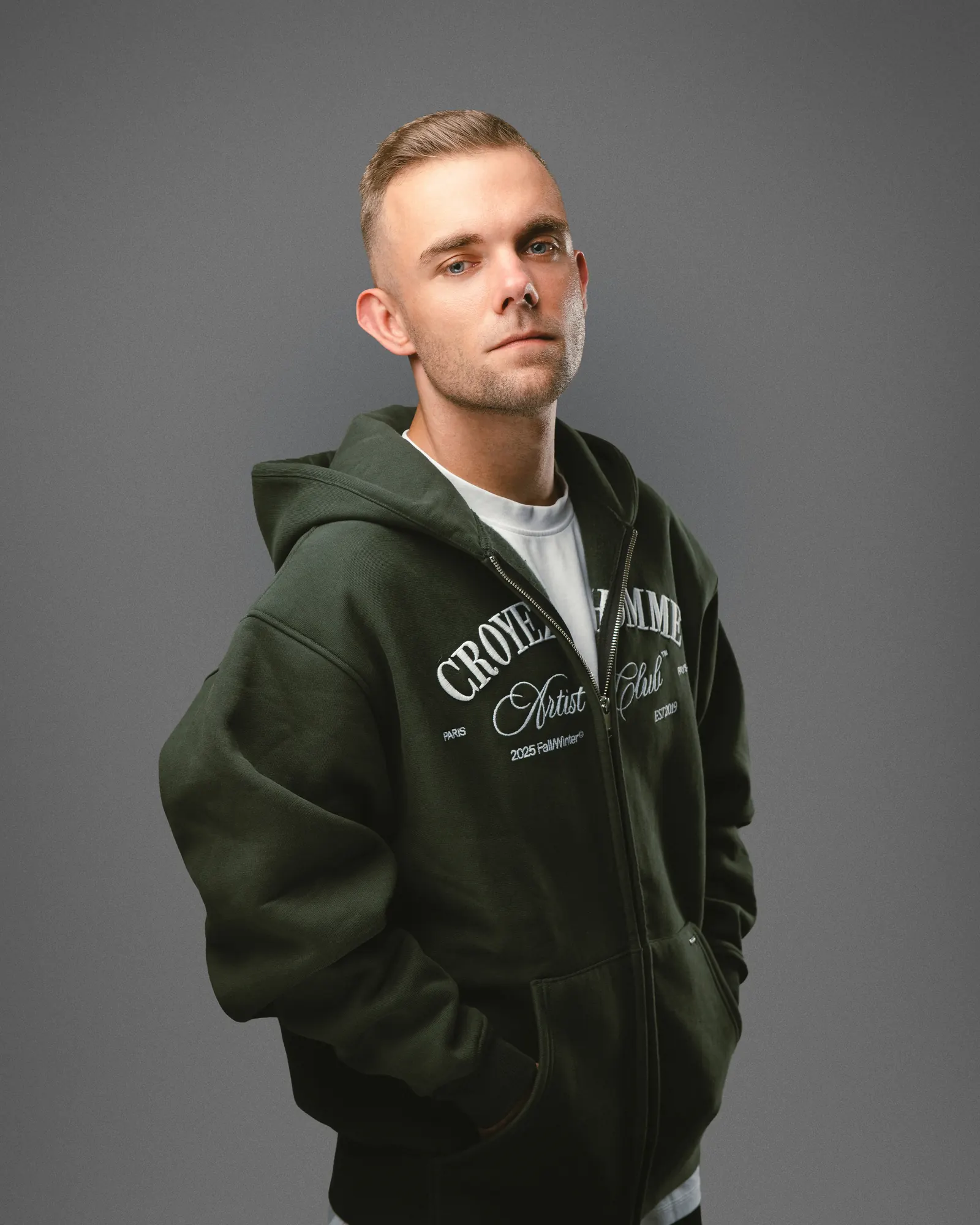 SDNX in donkergroene hoodie tegen grijze achtergrond, perskit 2026